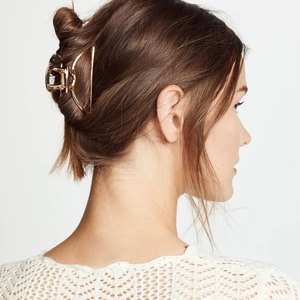 Minimalist large gold metal hair claw clip shown on a model for a modern hair style