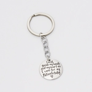 Detail of silver round keychain with engraved Lord guide my hands medical prayer text