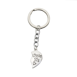 Polished silver heart keychain engraved with Little Sis and heart pattern on white background