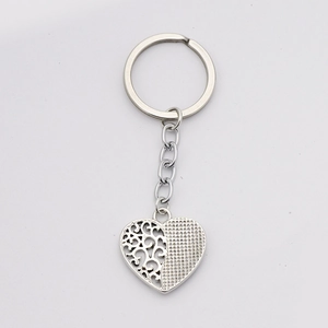 Silver heart keychain with hollow tree pattern and mesh texture on a grey background
