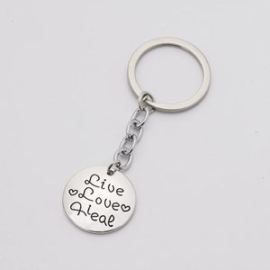 Detail of silver round pendant with Live Love Heal engraving and heart on metal keychain