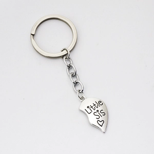 Macro detail of polished silver heart keychain with Little Sis engraving and link chain