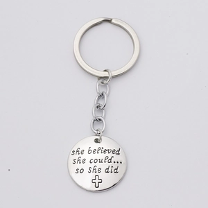 Close-up of silver steel keychain with 'She believed she could' quote and cross charm
