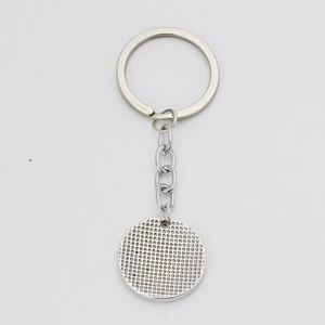 Macro shot of silver round keychain pendant with textured base for DIY photo settings