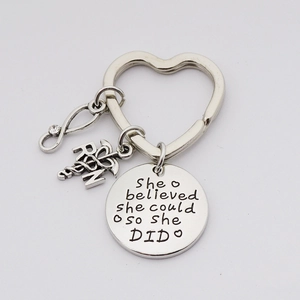 Detail view of the silver nurse keychain featuring RN caduceus and she believed engraving