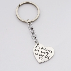 Detailed close-up of heart-shaped keychain with engraved motivational she believed quote