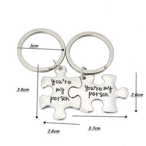 Close-up of puzzle piece keychains engraved with You're My Person text for couples