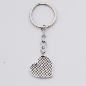 Detail showing polished silver heart pendant with textured grid embossing and sturdy metal ring