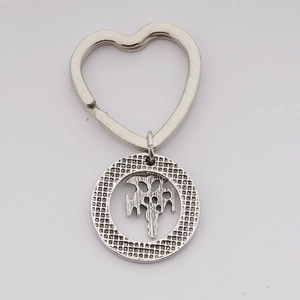 Detail of vintage silver alloy heart ring keychain with textured punk style circular pendant