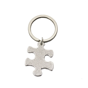 Macro view of puzzle piece keychain with textured metallic finish and silver polished ring