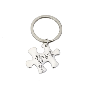 Macro shot of silver puzzle keychain engraved with Side by side or miles apart