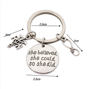 Detail of RN caduceus charm and engraved she believed plaque on nurse keychain