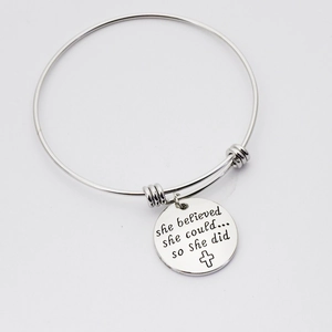 Detail of silver stainless steel charm bracelet with engraved she believed she could message