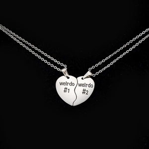 Dettaglio di collane puzzle a forma di cuore argento con incisione weirdo su velluto nero