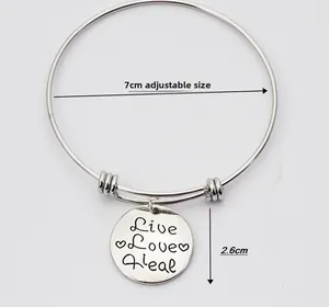 Macro shot showing dimensions of adjustable silver bangle with Live Love Heal pendant