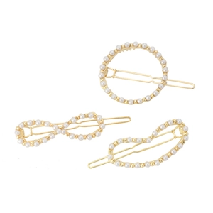 Detailed view of three gold-plated hair clips with pearls in geometric shapes