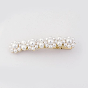 Détail de la barrette à cheveux avec perles blanches sur une base en métal doré
