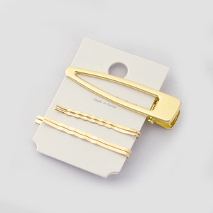 Detailed view of 3-piece golden metal hair clips set on a white card display