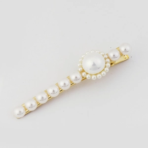 Vue macro d'une barrette dorée avec arrangement floral de perles blanches nacrées