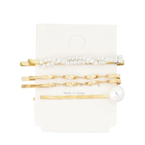 Detailed view of three gold pearl hair clips on white card including woven pearl design