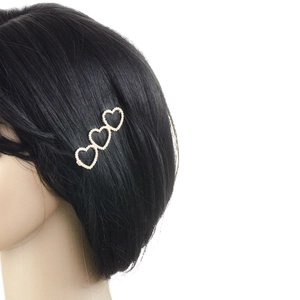 Détail d'une barrette à trois cœurs perlés sur cheveux sombres avec base dorée chic