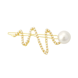 Détail d'une barrette dorée ornée de perles avec un design géométrique de battement de coeur