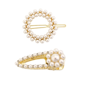 Gros plan de barrettes dorées en alliage avec perles et strass sur fond blanc épuré