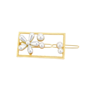 Detail of a gold alloy rectangular hair clip with white pearls and floral pattern