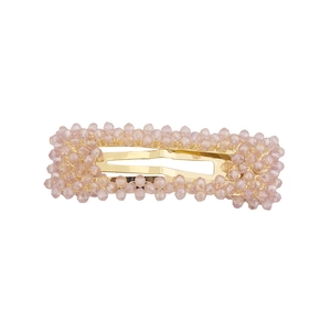 Dettaglio di perle di cristallo rosa su un fermaglio rettangolare dorato da donna