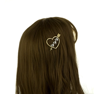 Détail de la pince à cheveux cœur dorée avec perles portée sur cheveux bruns