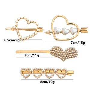Détail des barrettes à cheveux en alliage doré avec cœurs et perles sur fond blanc