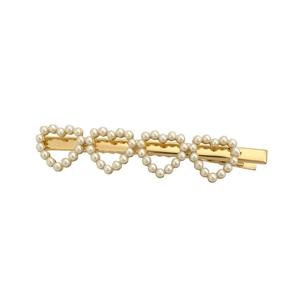 Barrette à cheveux dorée ornée de quatre cœurs en perles sur un fond blanc épuré