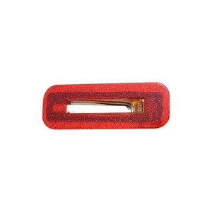 Détail macro d'une pince à cheveux en résine rouge pailletée avec clip en métal doré