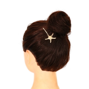 Macro shot of a golden starfish hair clip with frosted texture on dark hair bun