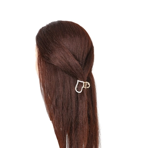 Détail d'une pince à cheveux en cœur avec perles sur des cheveux lisses foncés