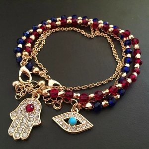 Close-up of Hamsa Hand and Evil Eye charms on layered red and blue beaded bracelet