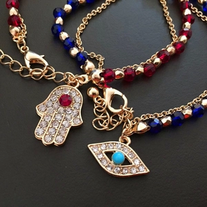 Detailed close-up of Hamsa Hand and Evil Eye charms on bohemian beaded crystal bracelets
