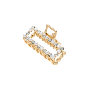 Détail d'une pince à cheveux géométrique dorée avec perles blanches et strass brillants