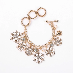 Detailed view of a gold snowflake bracelet with white enamel charms and pearls