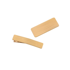 Close-up of golden rectangular metal hair clips with a fine brushed texture finish
