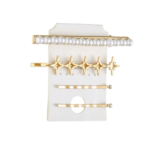Elegante set di 4 fermagli per capelli dorati con perle e stelle su cartoncino