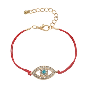 Detail of red braided cord bracelet featuring a gold evil eye charm with blue zircon stones
