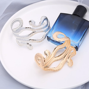 Overdreven slangvormige open metalen armbanden in goud en zilver met gegraveerde schubben