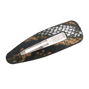Macro shot of a drop-shaped hair clip with vintage snakeskin leather and silver alloy base