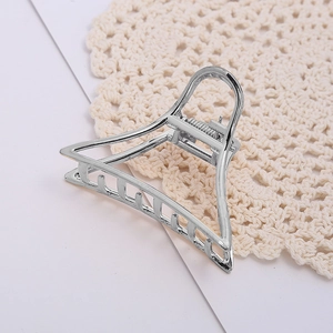 Pince à cheveux triangle en métal argenté élégant sur un fond minimaliste moderne