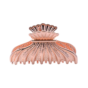 Vue détaillée d'une pince à cheveux en métal or rose en forme de coquille polie