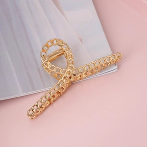 Elegant gold metal hair claw clip with a chain link design on a soft aesthetic background
