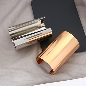 Detail of high-polished gold and silver wide metal open cuffs with mirror finish