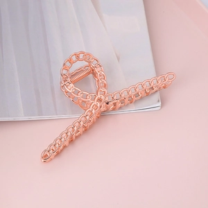Elegant rose gold metal chain hair claw clip for women on minimalist pink background