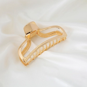 Minimalistische große goldene Haarklammer aus Metall mit hohlem Design auf weißer Seide